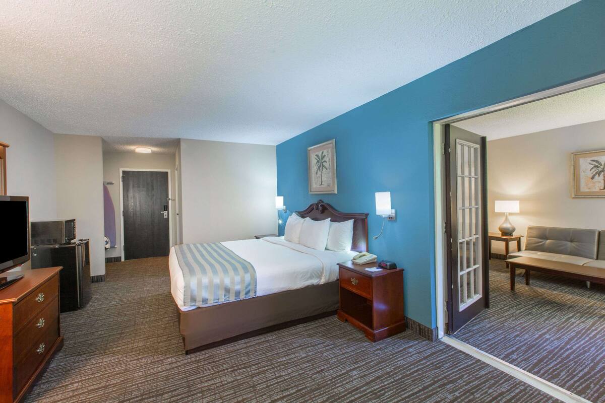 Une chambre d’hôtel avec un lit, une table de chevet, une lampe et un téléviseur posé sur une commode.