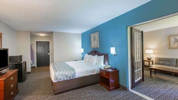 A hotel room with a bed, bedside table, lamp, and a television on a dresser.