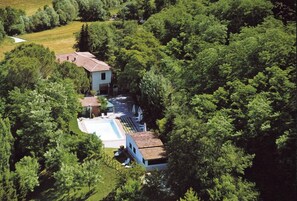 Uma casa isolada rodeada por floresta densa, com piscina e um pequeno espaço de terraço.