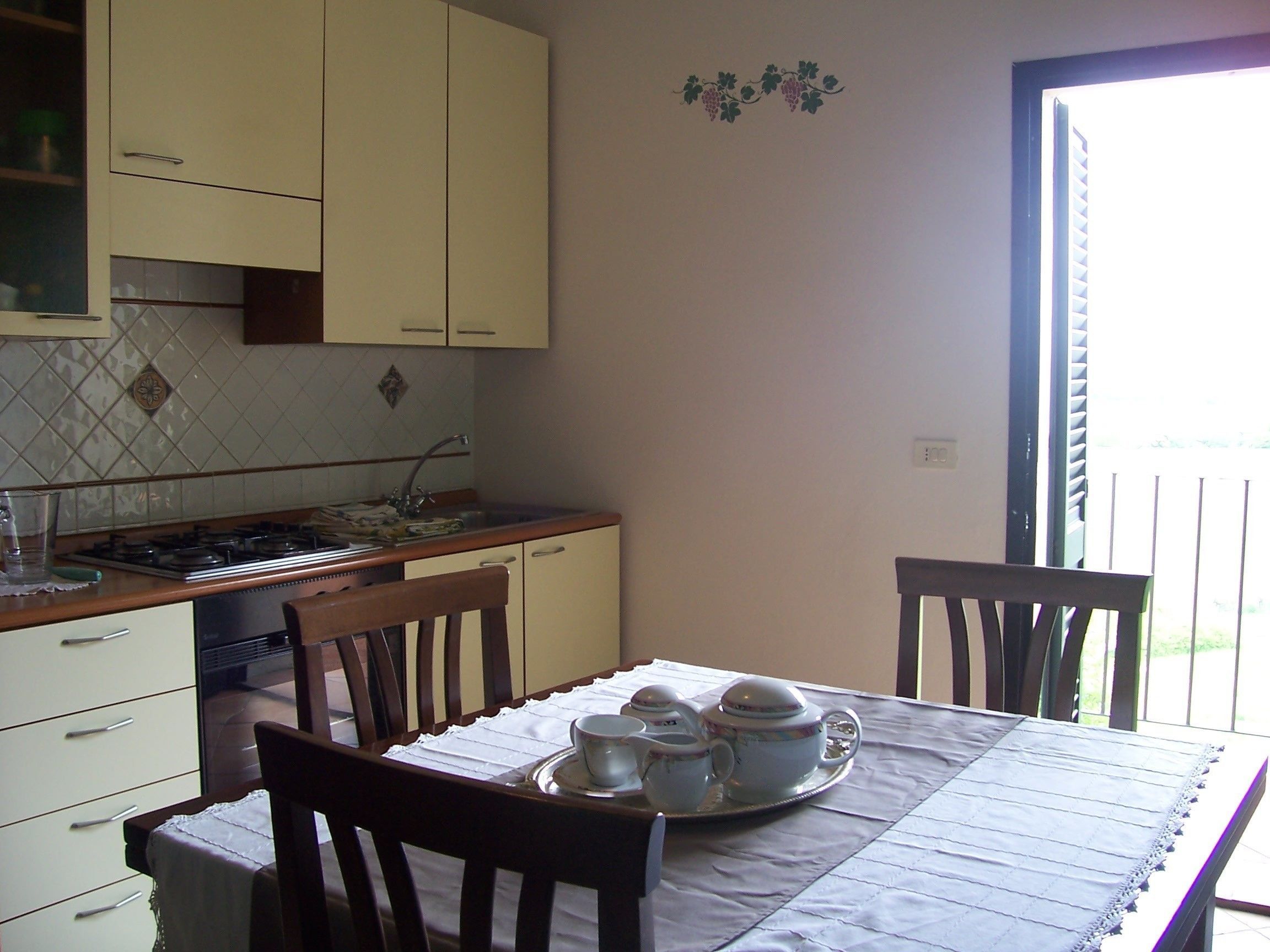 A kitchen with a dining table set for tea, a stove, and cabinets.