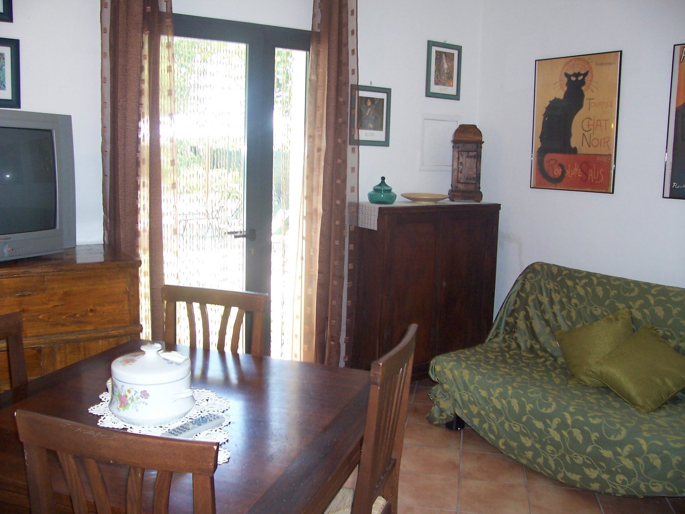 A dining area with a wooden table, chairs, a television, and a sofa.