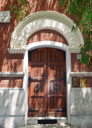 A double wooden door with a white archway, a brass knocker, and a sign indicating "Suites Farnese 2 Piano". - Suites Farnese Design  (Rome)