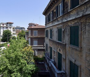 A multi-story building with green shutters, a balcony, and a statue. - Suites Farnese Design  (Rome)