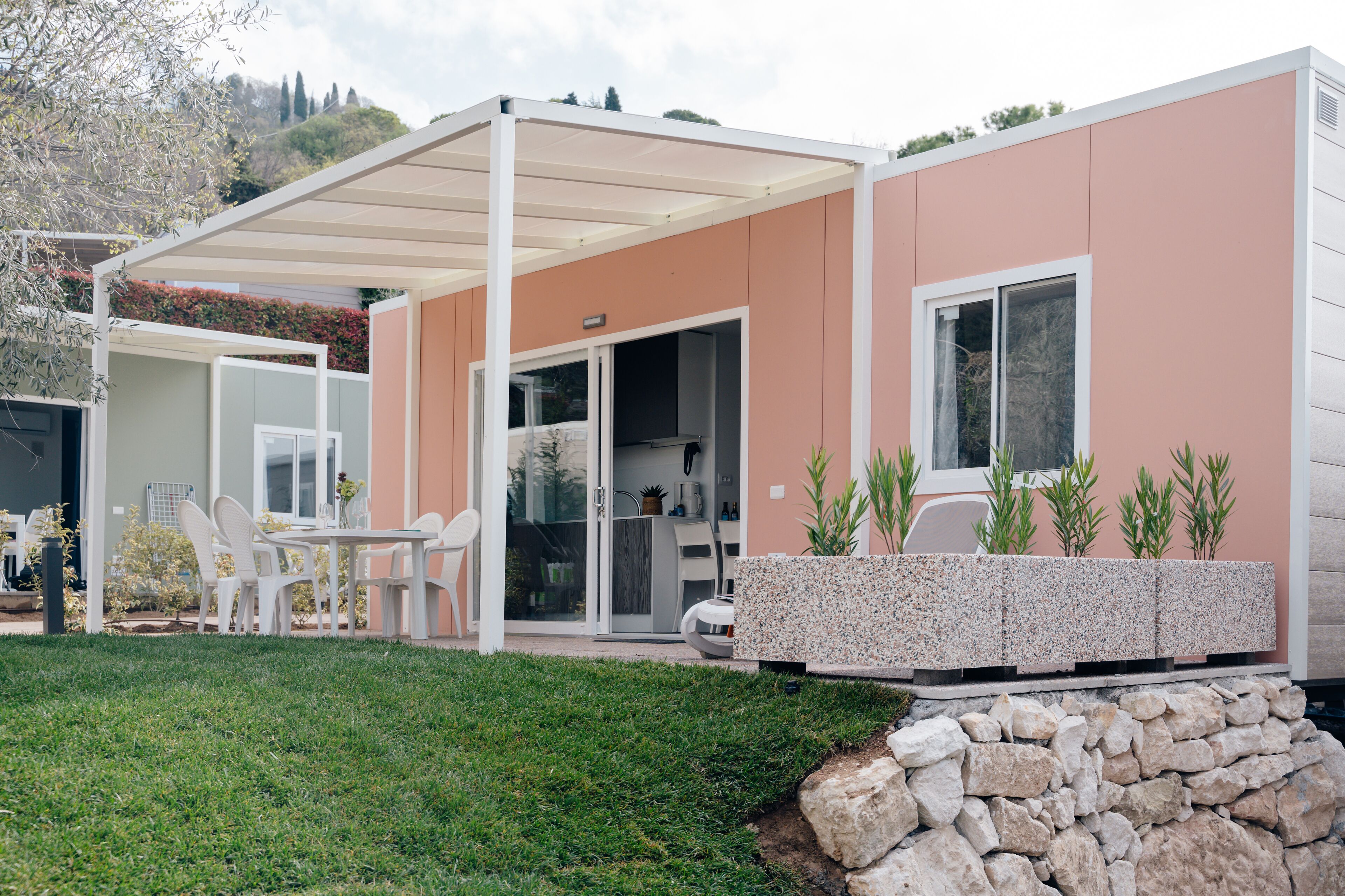 Una casa moderna con un patio cubierto, mobiliario exterior y una pared de piedra.