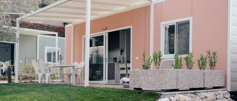 Una casa moderna con un patio cubierto, mobiliario exterior y una pared de piedra.