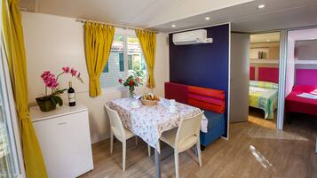 A compact room with a dining table, a small refrigerator, a sofa, and a bed.