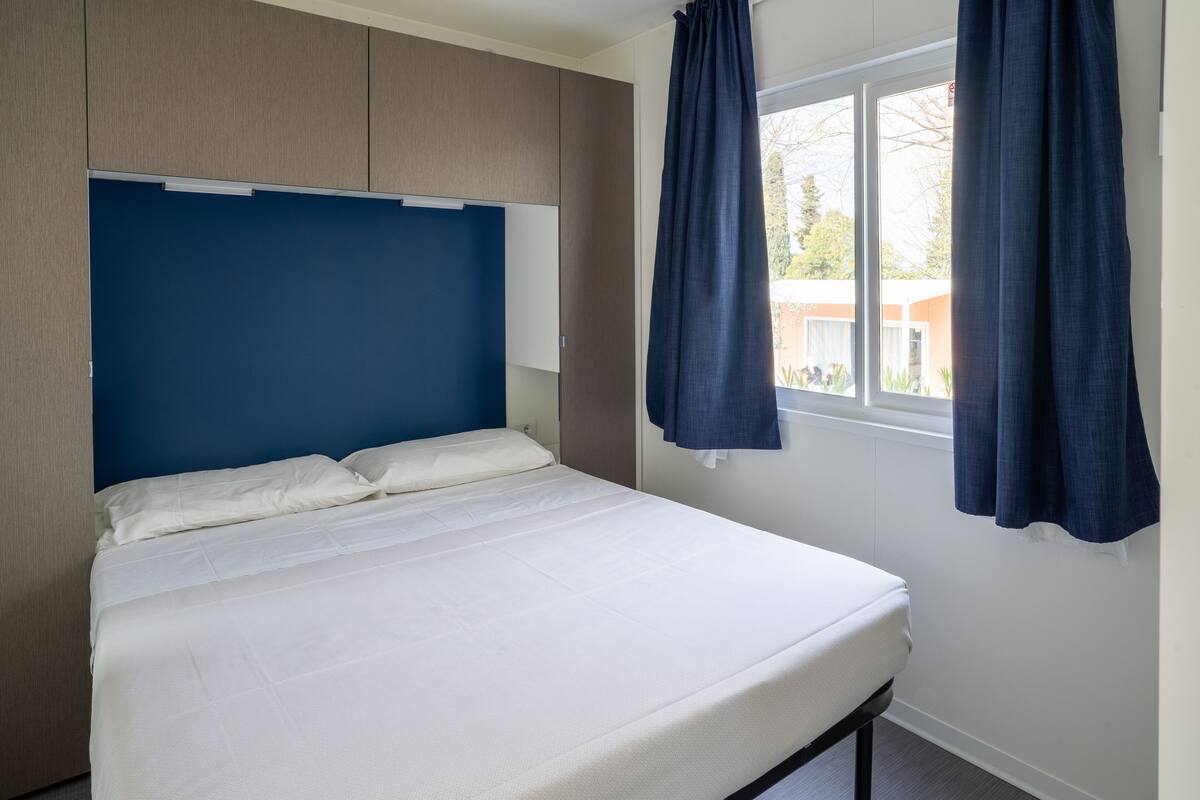 A bedroom with a bed, a wardrobe, and a window with curtains.