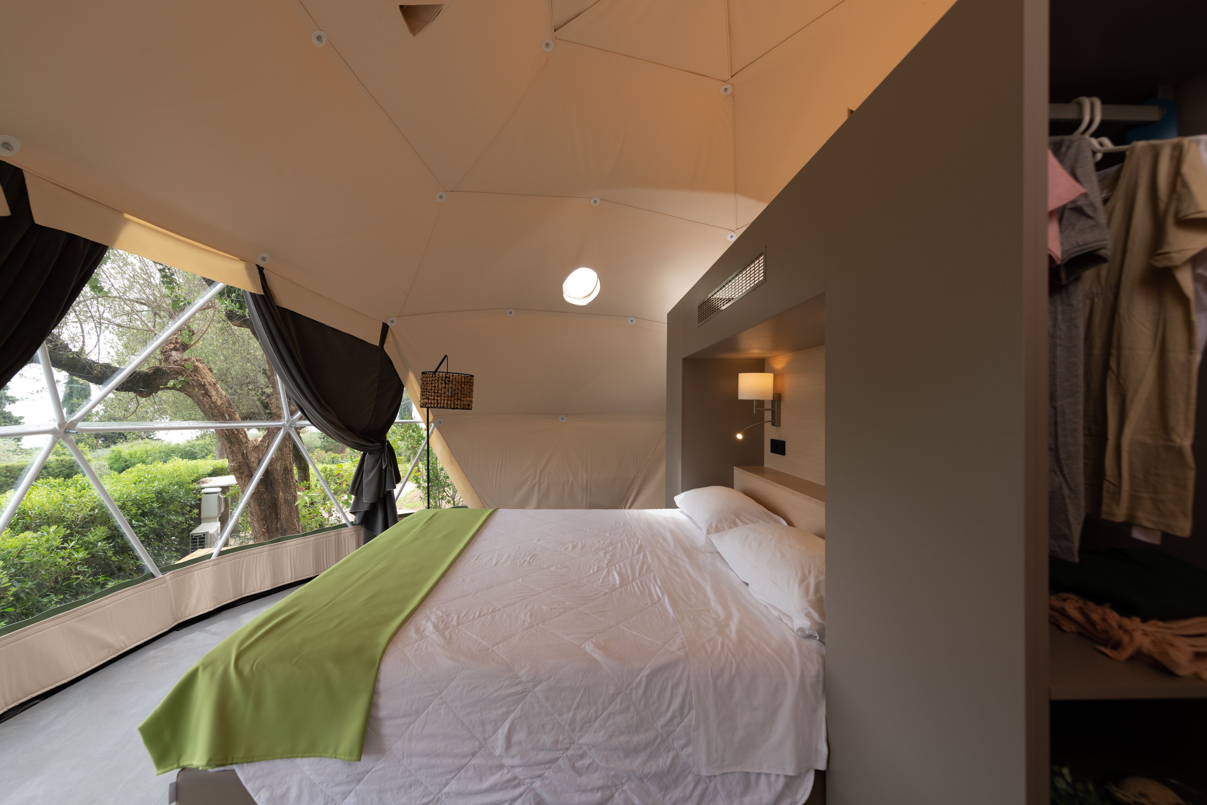 Un dormitorio con una cama grande, una ventana con cortinas, una cesta colgante y un armario.