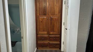 A hallway with a wooden wardrobe, a white door, and a tiled floor.
