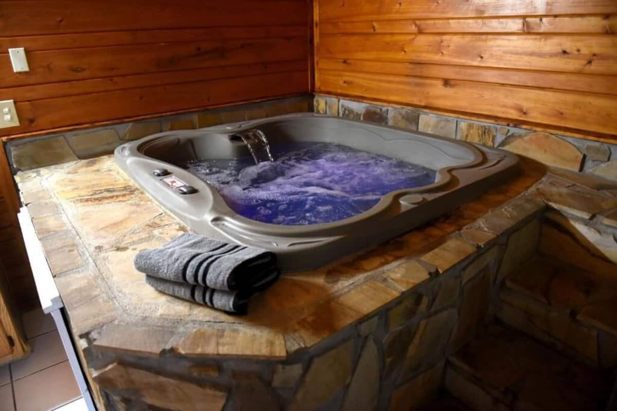 A stone-tub with a wooden interior, a control panel, and a towel on the counter.