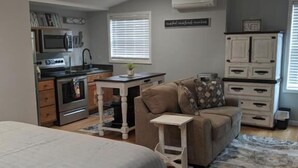 A bedroom with a bed, a ceiling fan, a kitchenette, a couch, and a rug. - Heidi Motel (Helen)