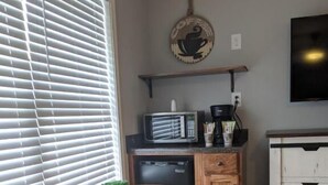 A compact kitchen with a microwave, coffee maker, and a small table with a plant. - Heidi Motel (Helen)