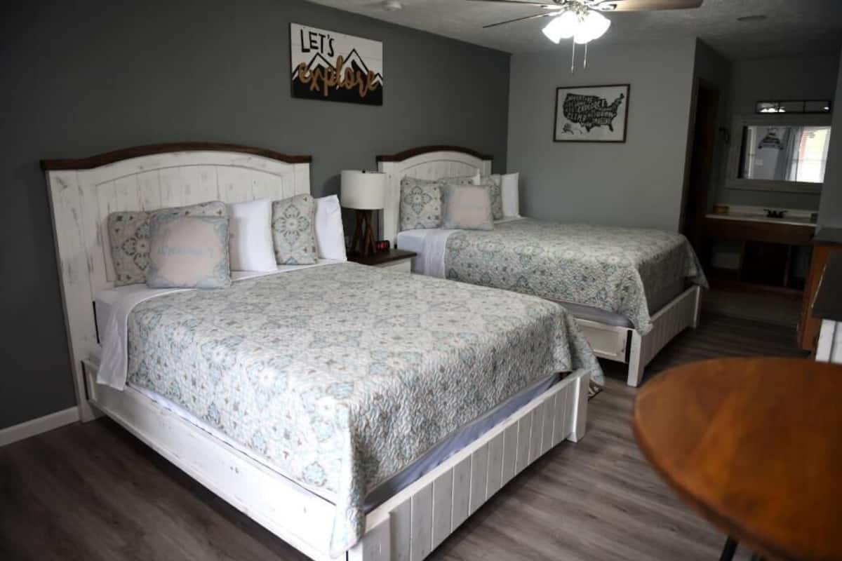 A bedroom with two beds, a ceiling fan, and a small table.