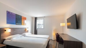A hotel room with two beds, a desk, a chair, a TV, and artwork on the wall. - The Originals Residence, Appart'Hôtel Hévéa, Valence (Valence)