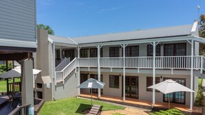A two-story house with a covered patio, a swimming pool, and outdoor seating. - Loerie Guest Lodge (George)