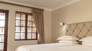 A bedroom with a bed, a ceiling fan, a window with curtains, and a door. - Loerie Guest Lodge (George)