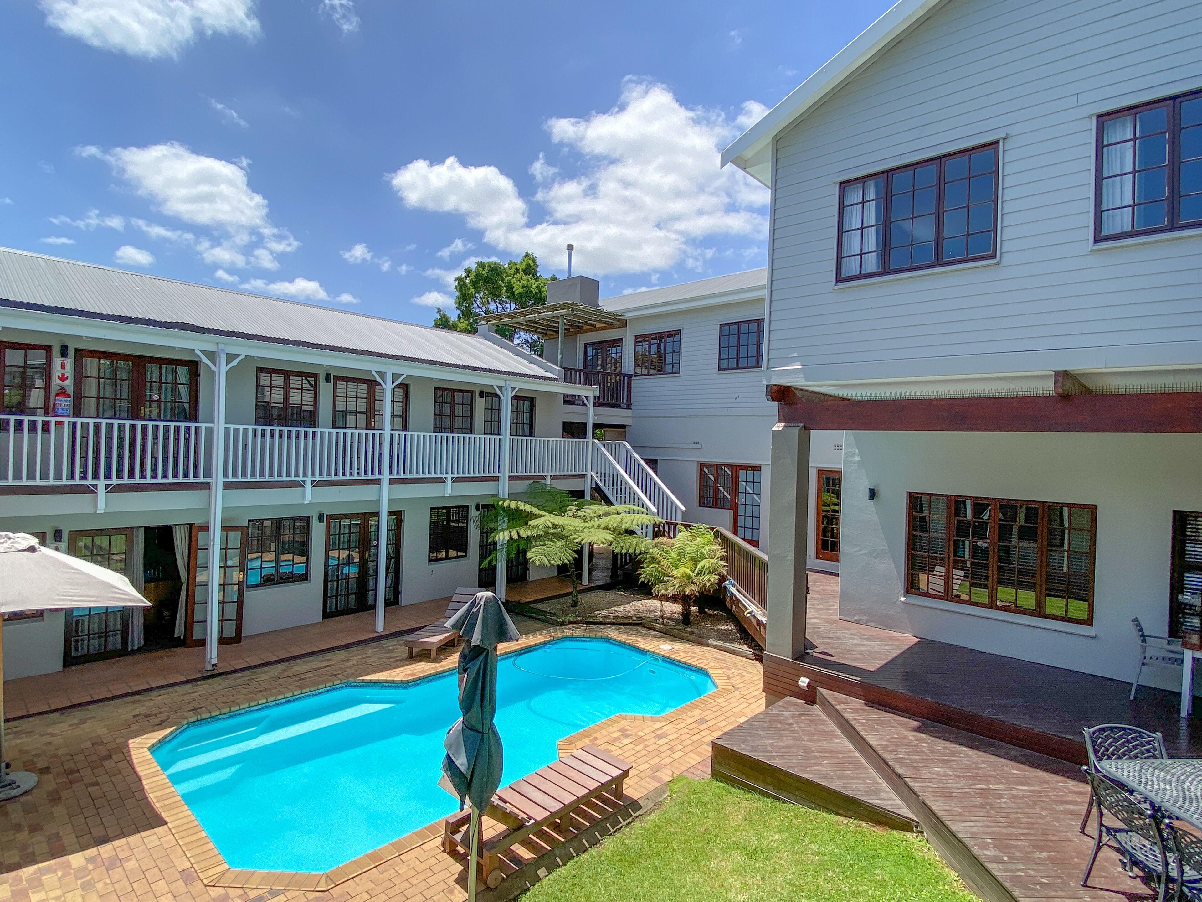 A two-story building with a swimming pool, outdoor seating, and a covered patio area.