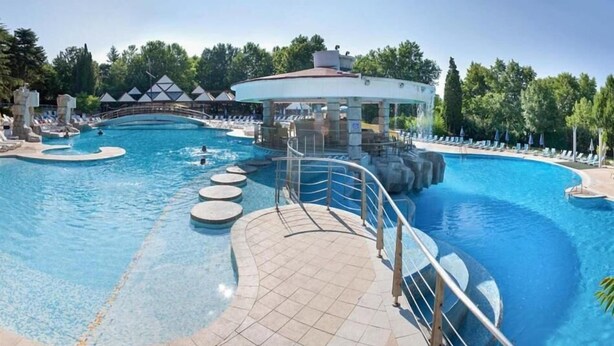 Una gran piscina curvada con una isla central y un pabellón.