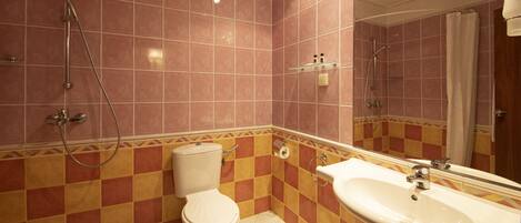 A bathroom with pink and yellow checkered tiles, a white toilet, a sink, and a shower.