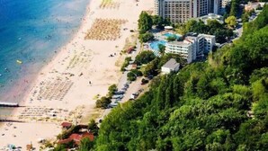 Un resort costero con una extensa playa de arena, varios edificios de hotel y abundante vegetación.
