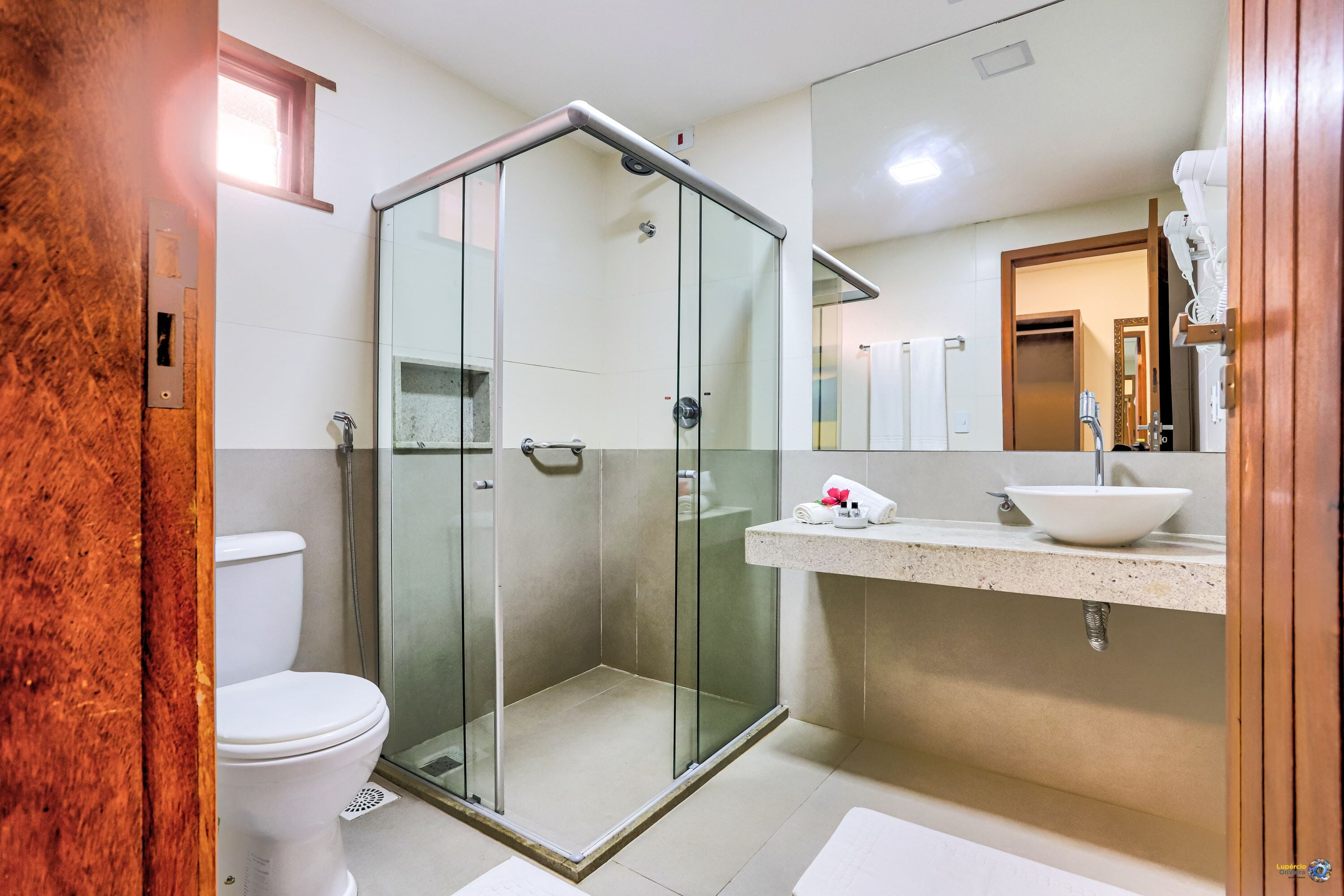 A modern bathroom with a glass-enclosed shower, a white toilet, and a sink with a white basin.