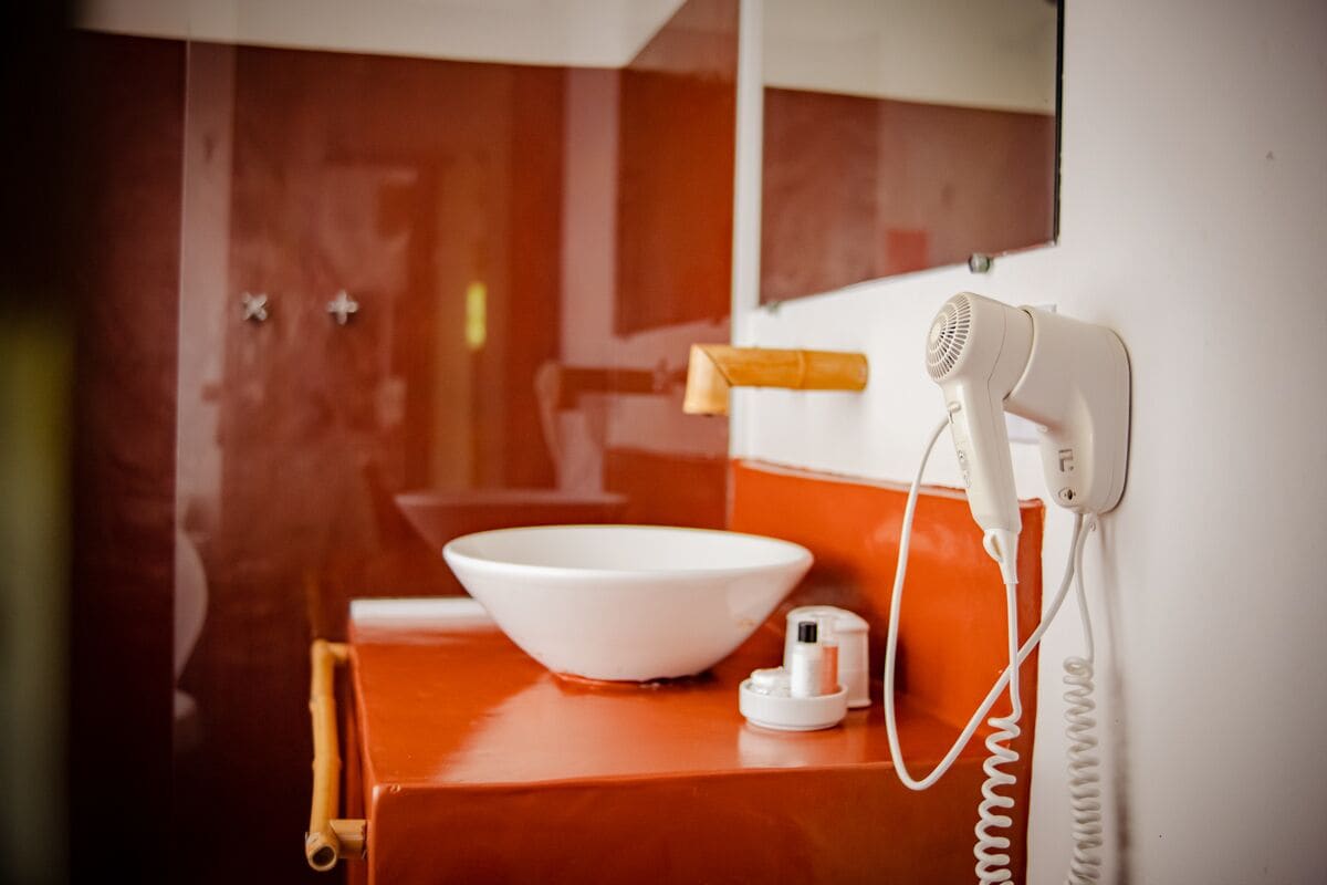 A bathroom with a white sink, a hairdryer, and a mirror.