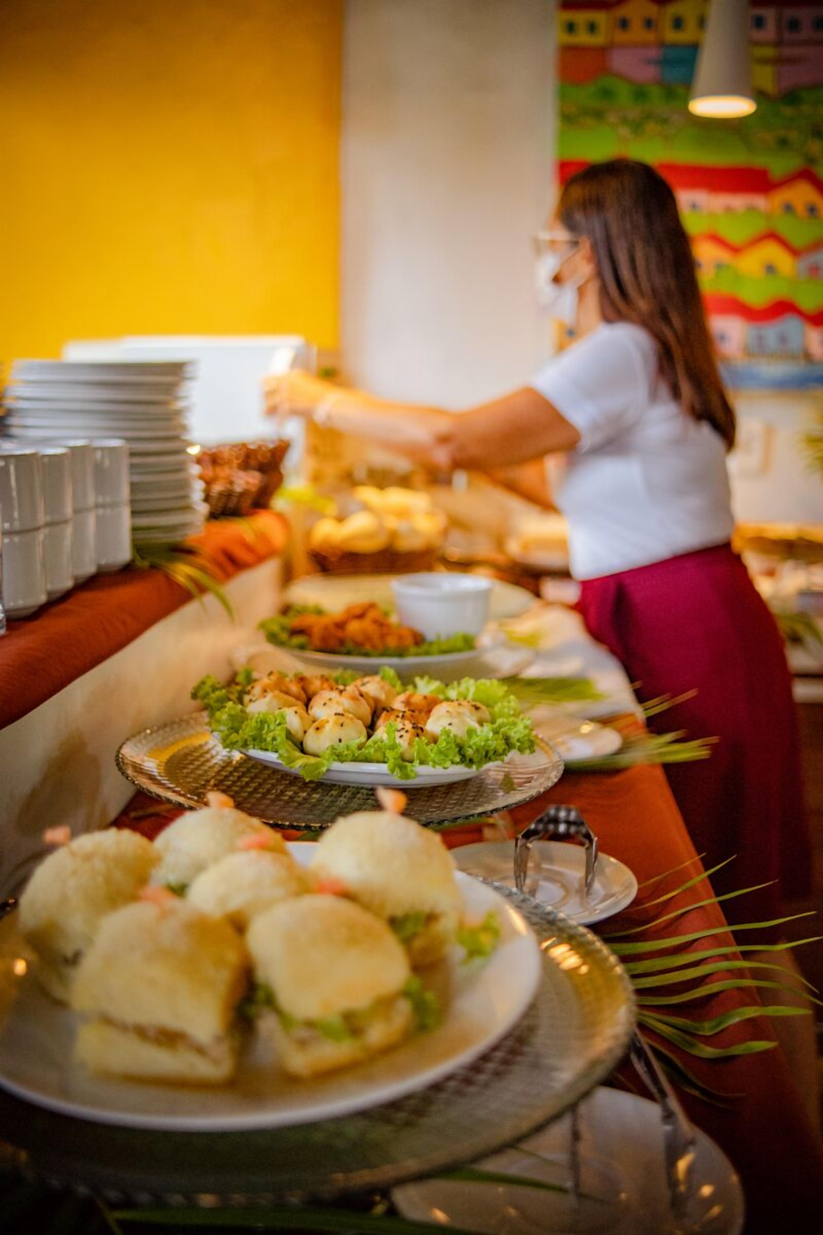 A buffet setup with various food items and a person serving.