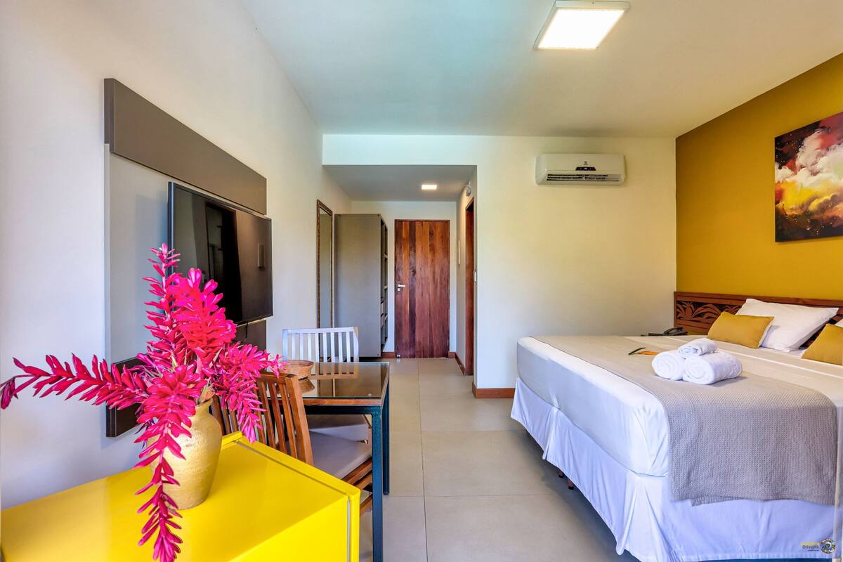 Una camera d'albergo con un letto, una scrivania, una sedia, una TV e un quadro appeso al muro.