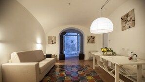 A modern living room with a sofa, a dining table, and a colorful rug. - La Casa di Carla (Ravello)