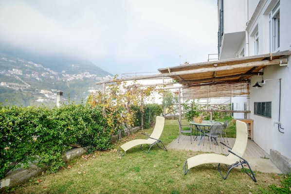 A patio with two lounge chairs, a table, and a pergola.