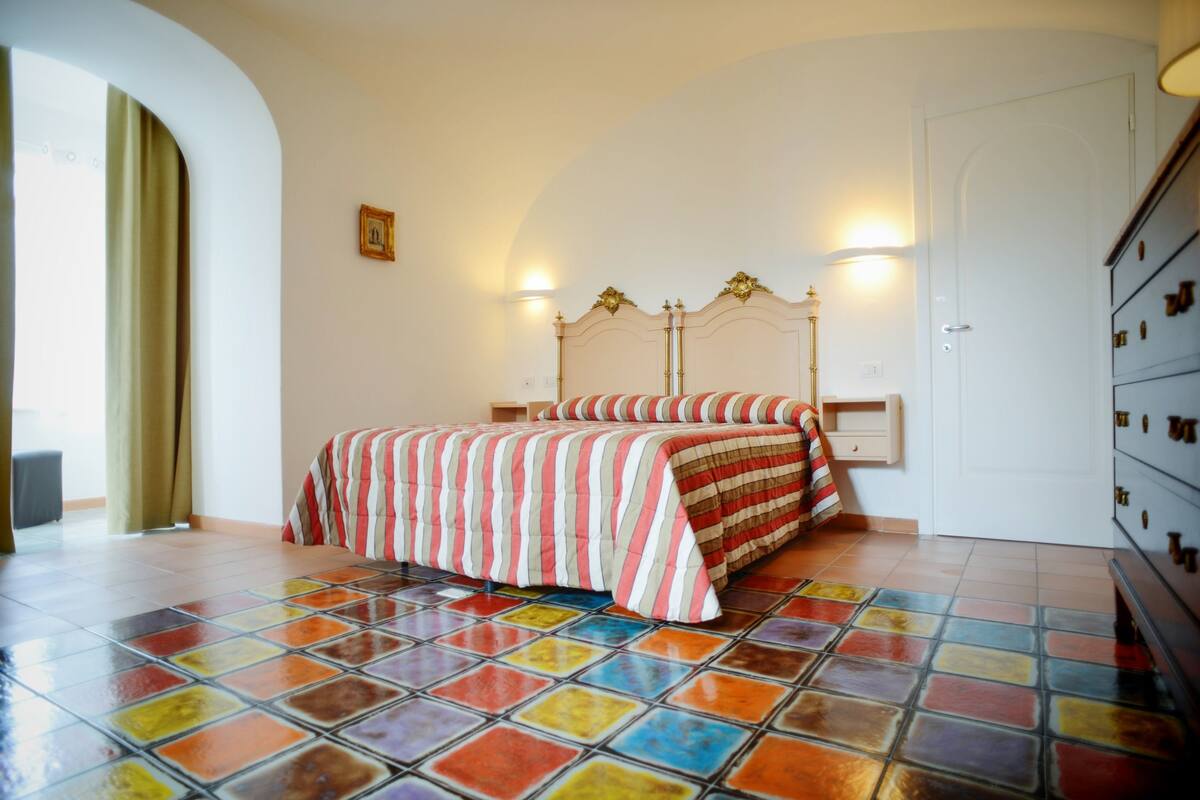 A bedroom with a bed, a dresser, and a door.