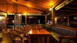Una terraza de madera al aire libre con piscina, zona de estar y ventilador de techo.