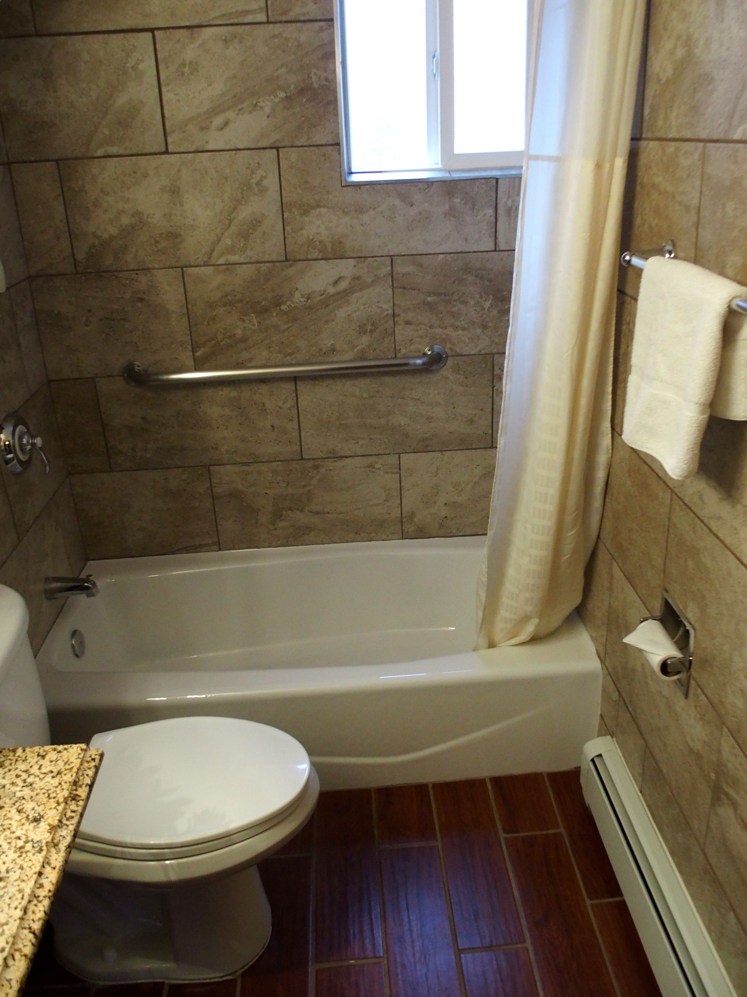 Un baño con bañera, inodoro y ventana.