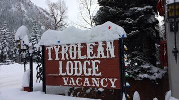 Ein hölzernes Schild mit der Aufschrift 'TYRULEAN LODGE VACANCY', teilweise von Schnee bedeckt.