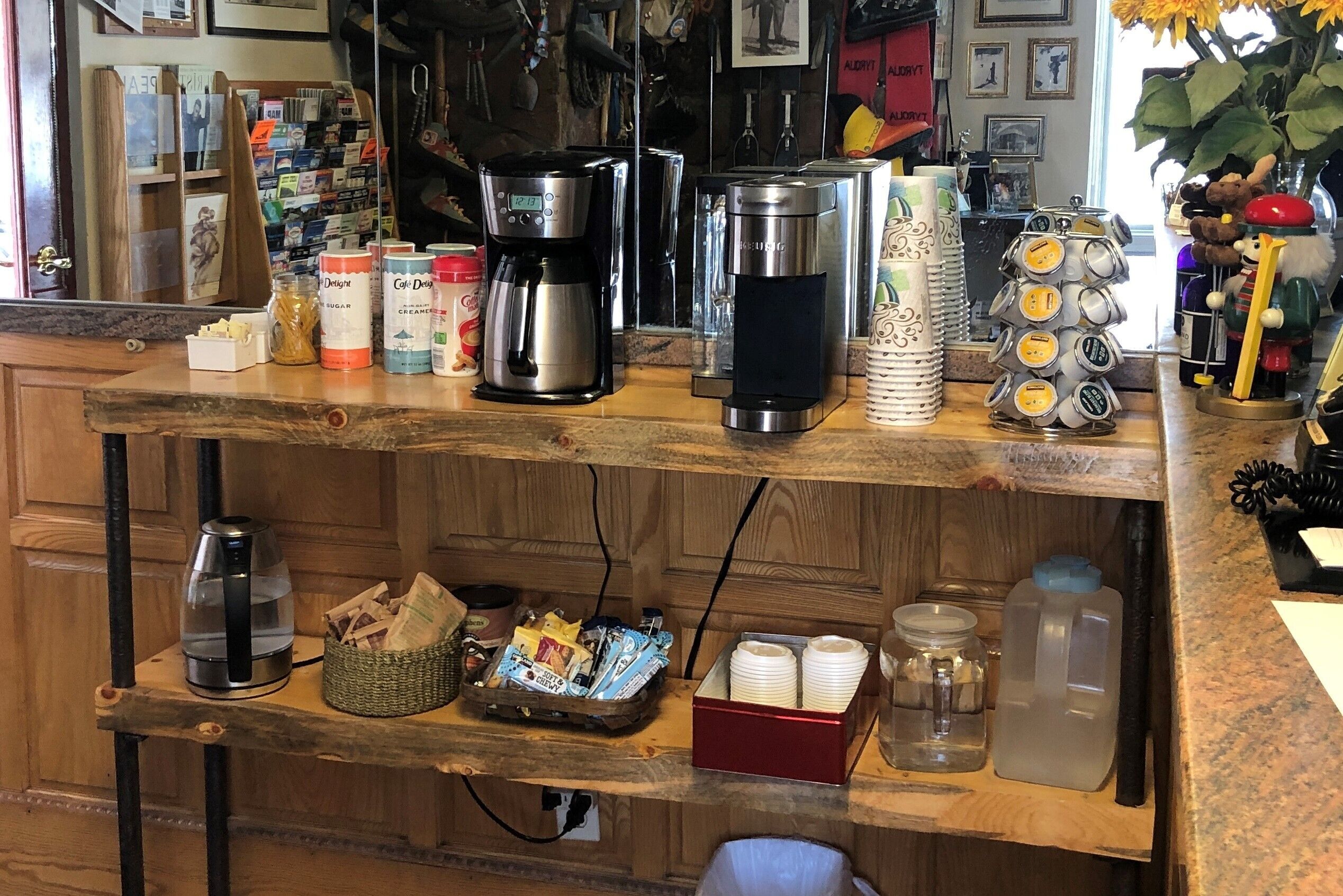 Un comptoir de cuisine avec différents types de cafetières, une machine à café et une pile de gobelets en papier.