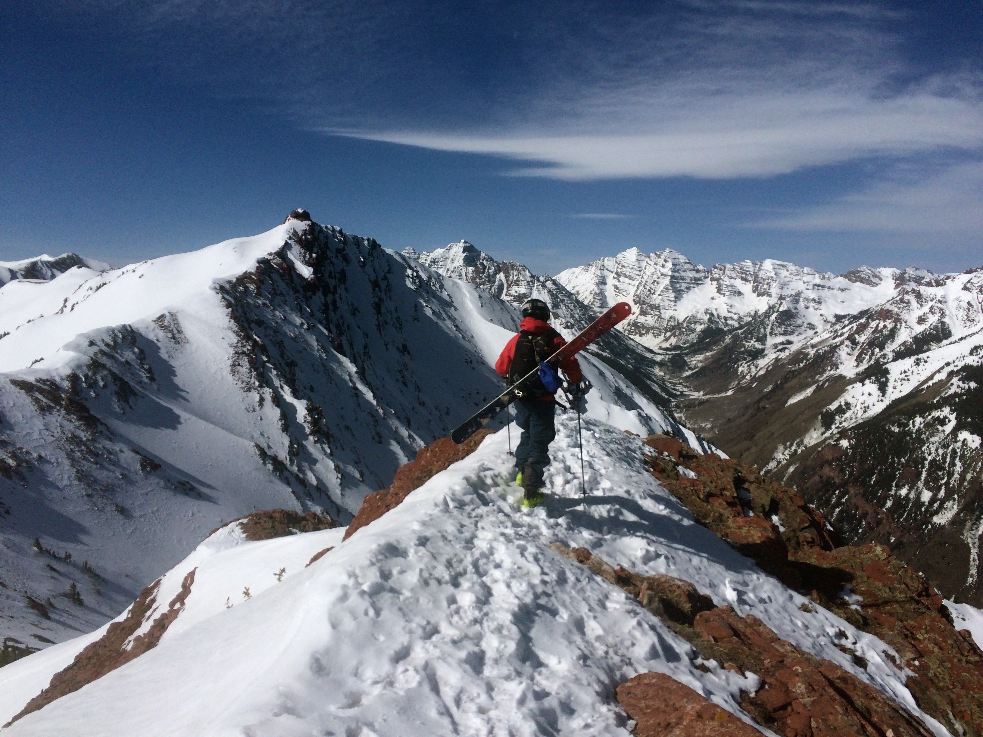 Una persona con esquíes en la cima nevada de una montaña.