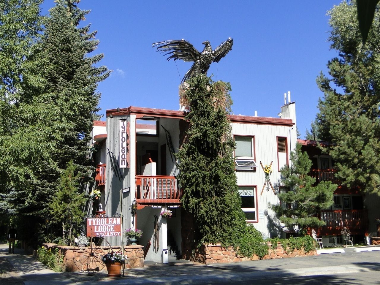 A lodge with a balcony, a bird sculpture, and a sign indicating vacancy.