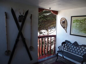 A room with a wooden bench, a wall-mounted rack with skis, and a framed map.