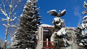 Una cabaña con entrada cubierta de nieve, un balcón y un cartel que indica habitaciones disponibles.