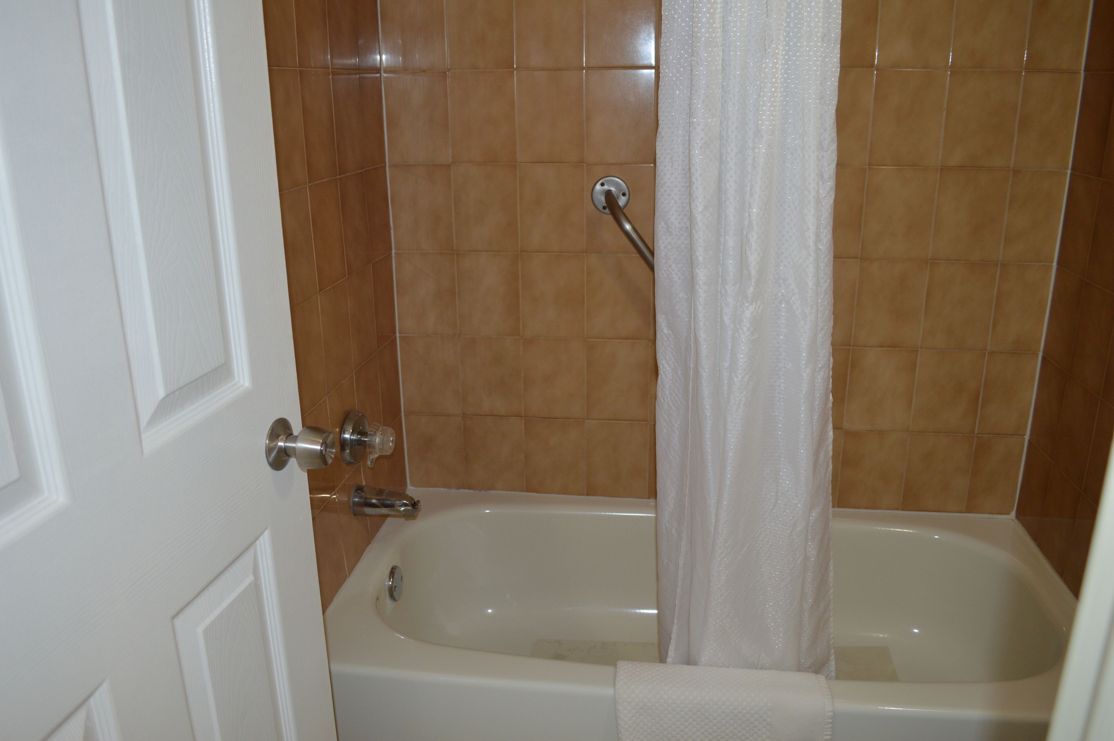 A bathroom with a bathtub, a shower curtain, and a white door.