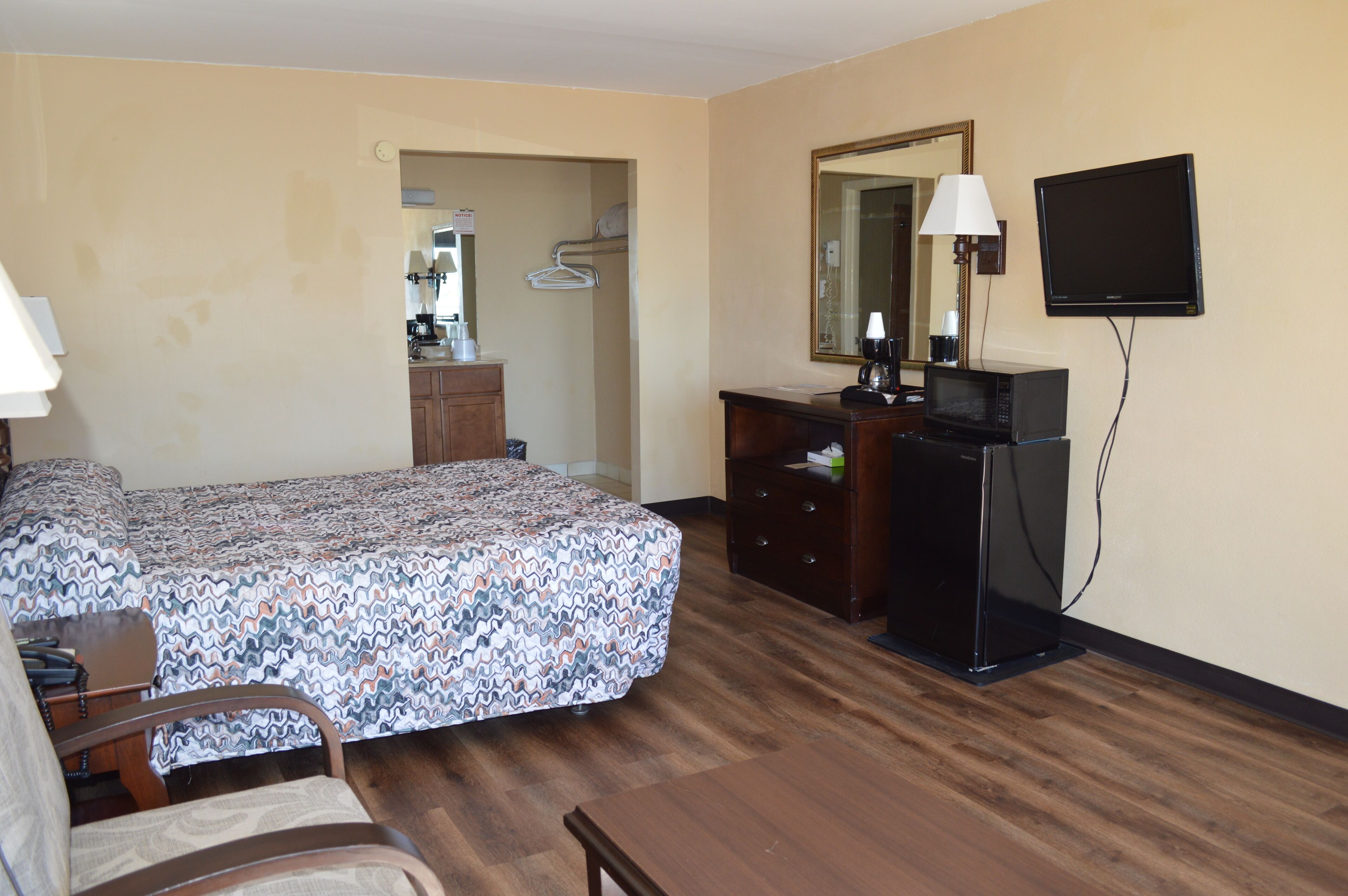 Ein Hotelzimmer mit Bett, Kommode, Fernseher und Spiegel.