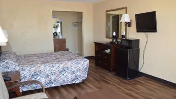 Ein Hotelzimmer mit Bett, Kommode, Fernseher und Spiegel.
