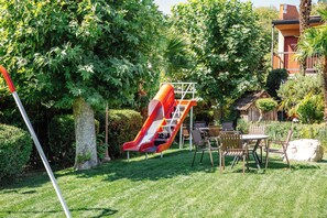 Un parque infantil con un tobogán y una mesa de picnic con sillas.