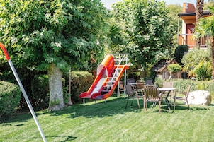 Un parque infantil con un tobogán y una mesa de picnic con sillas.