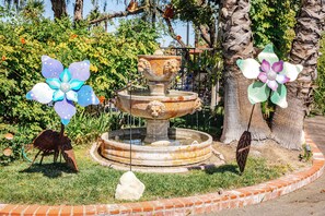 A garden with a fountain, a statue, and decorative elements.
