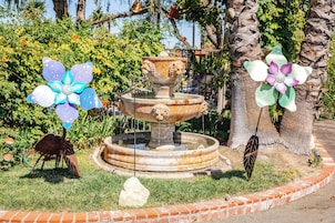 Un jardín con una fuente, una estatua y elementos decorativos.