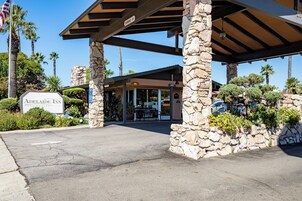 El Adelaide Inn, con fachada de piedra, entrada cubierta y cielo despejado.
