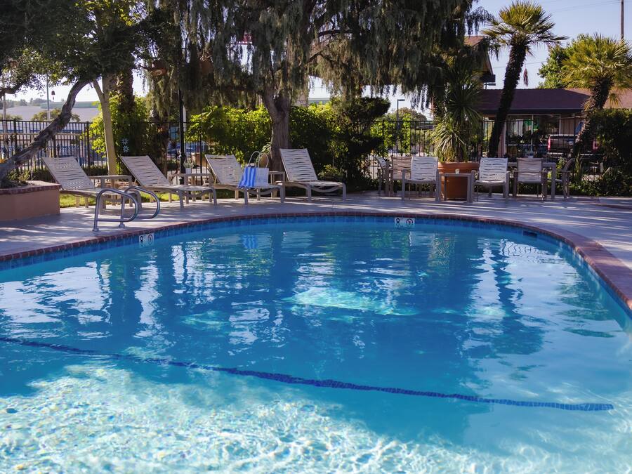 A clear swimming pool with lounge chairs and a tiled deck.