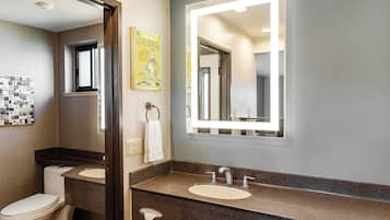 A bathroom with two sinks, a toilet, a towel rack, and a mirror.