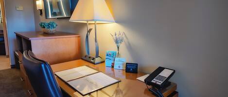 A hotel reception desk with a lamp, a phone, a notepad, a welcome brochure, and a non-smoking sign.